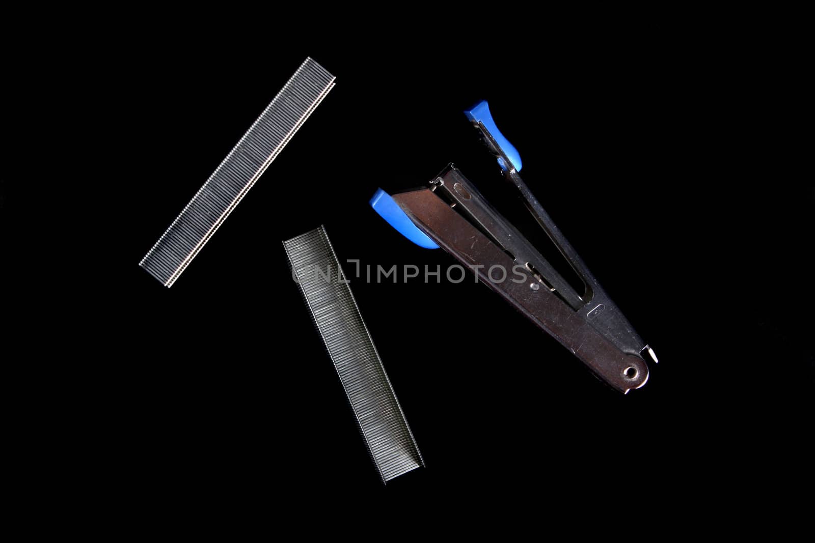 A blue stapler with a set of pins, on black studio background.