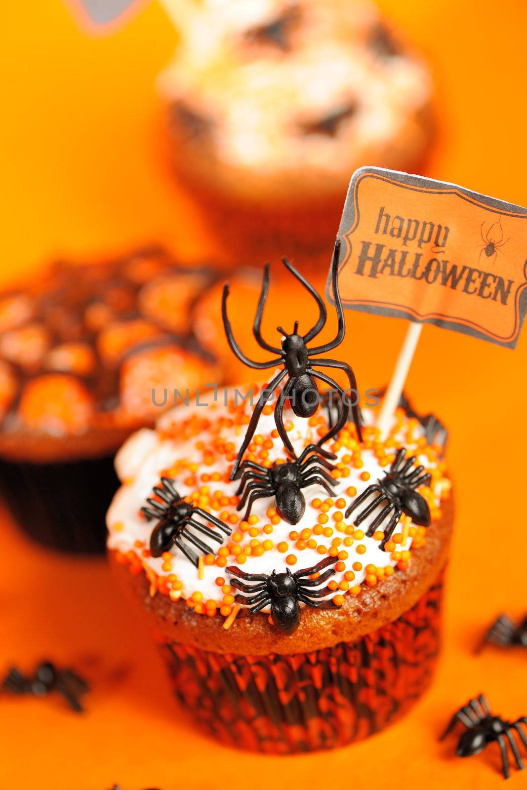 Halloween cupcakes with decoration over orange background