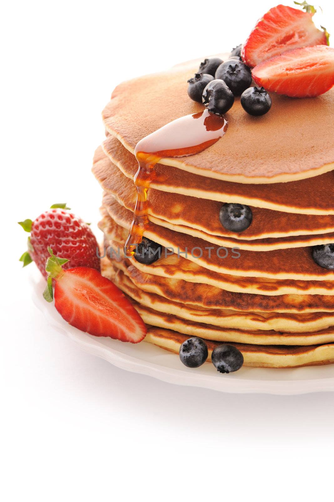 Delicious freshly prepared pancakes with strawberry and blueberries isolated on white