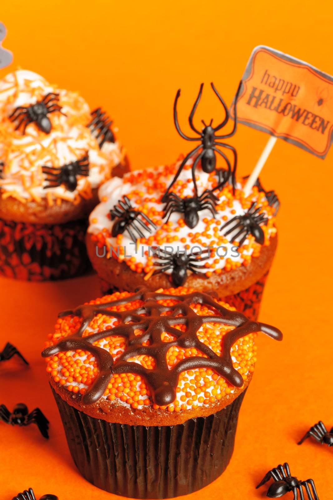 Halloween cupcakes with decoration over orange background