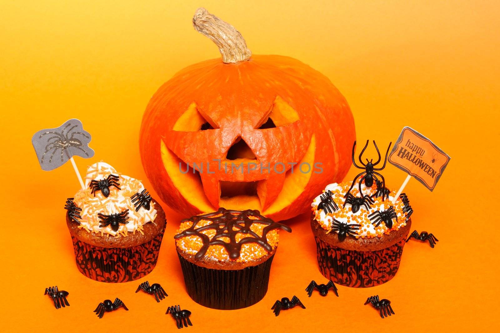 Halloween cupcakes with decoration over orange background