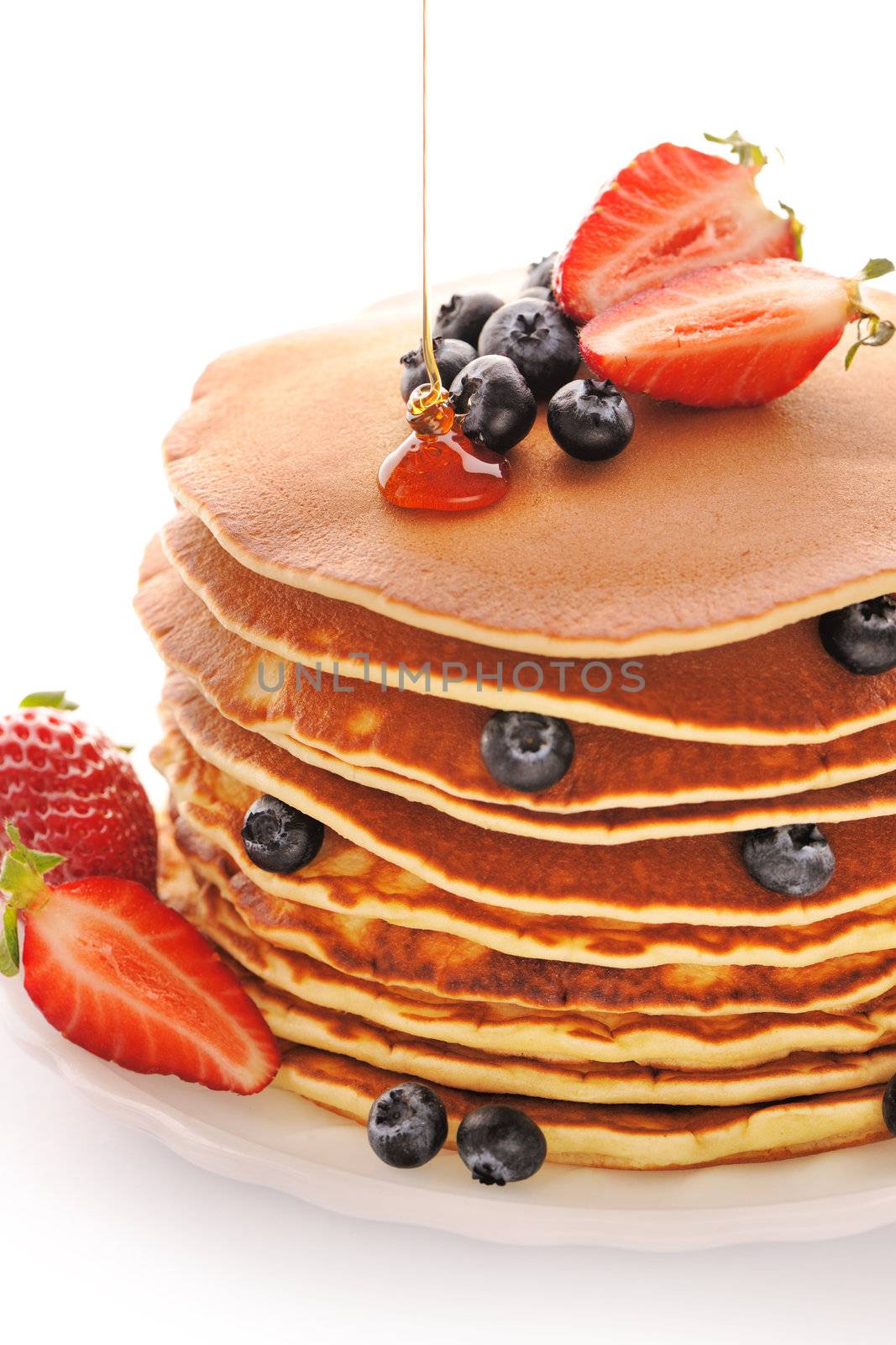 Delicious freshly prepared pancakes with strawberry and blueberries isolated on white