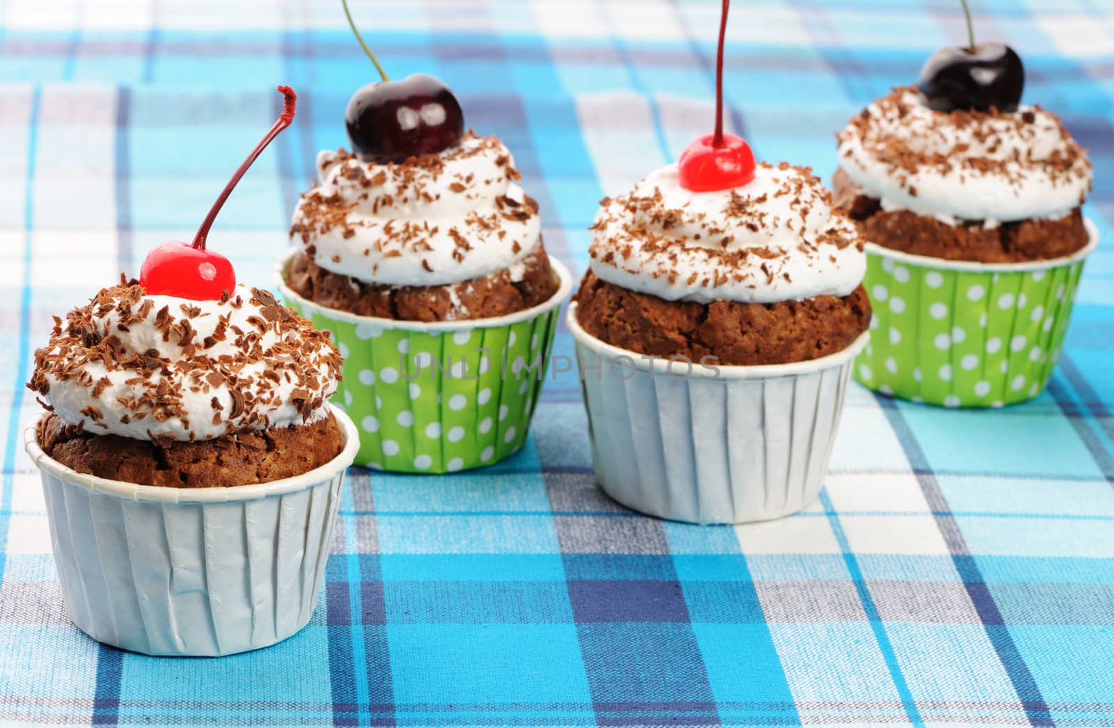 Cupcakes with whipped cream and cherry on a cloth
