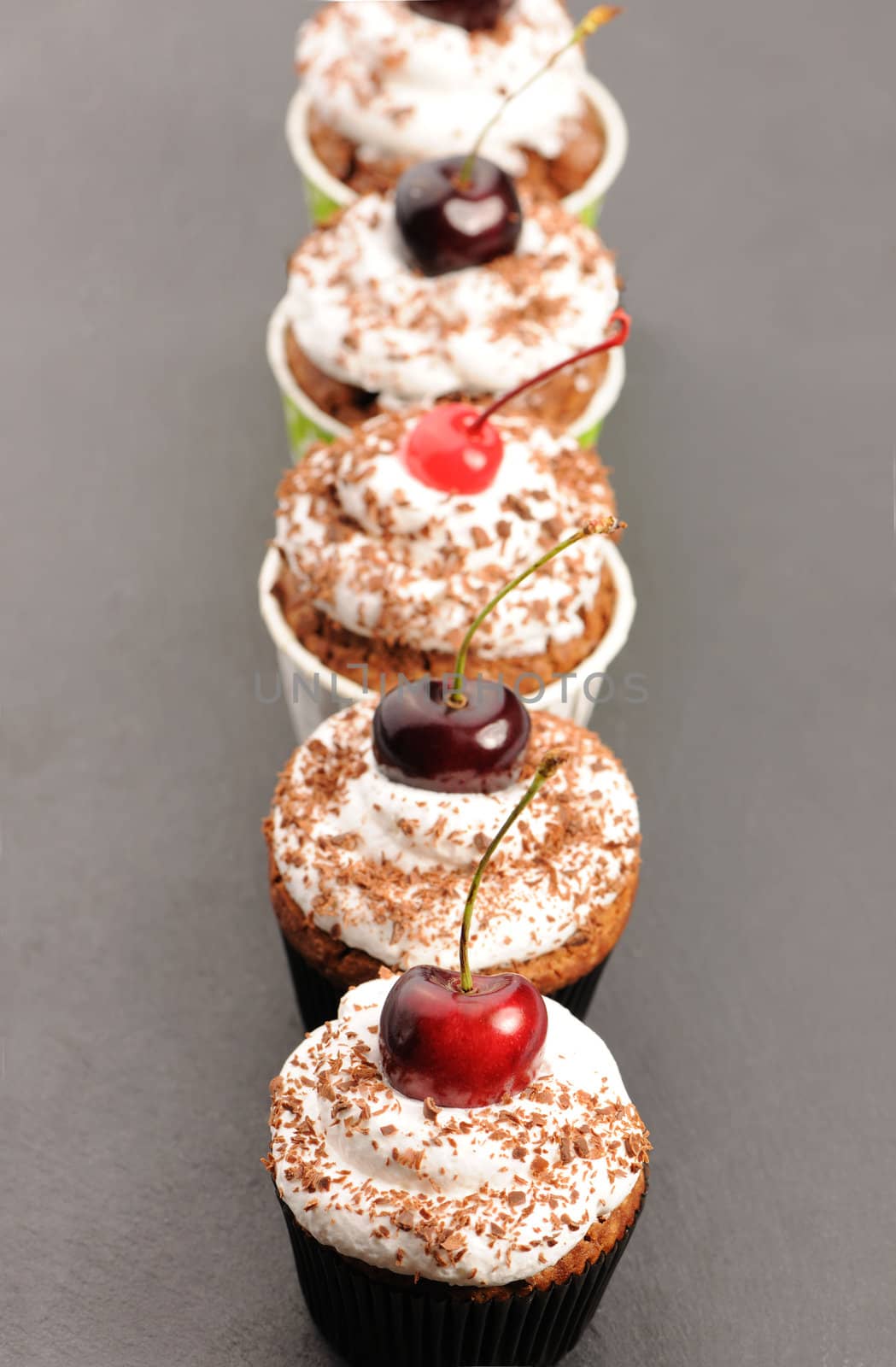 Cupcakes with whipped cream and cherry on a table