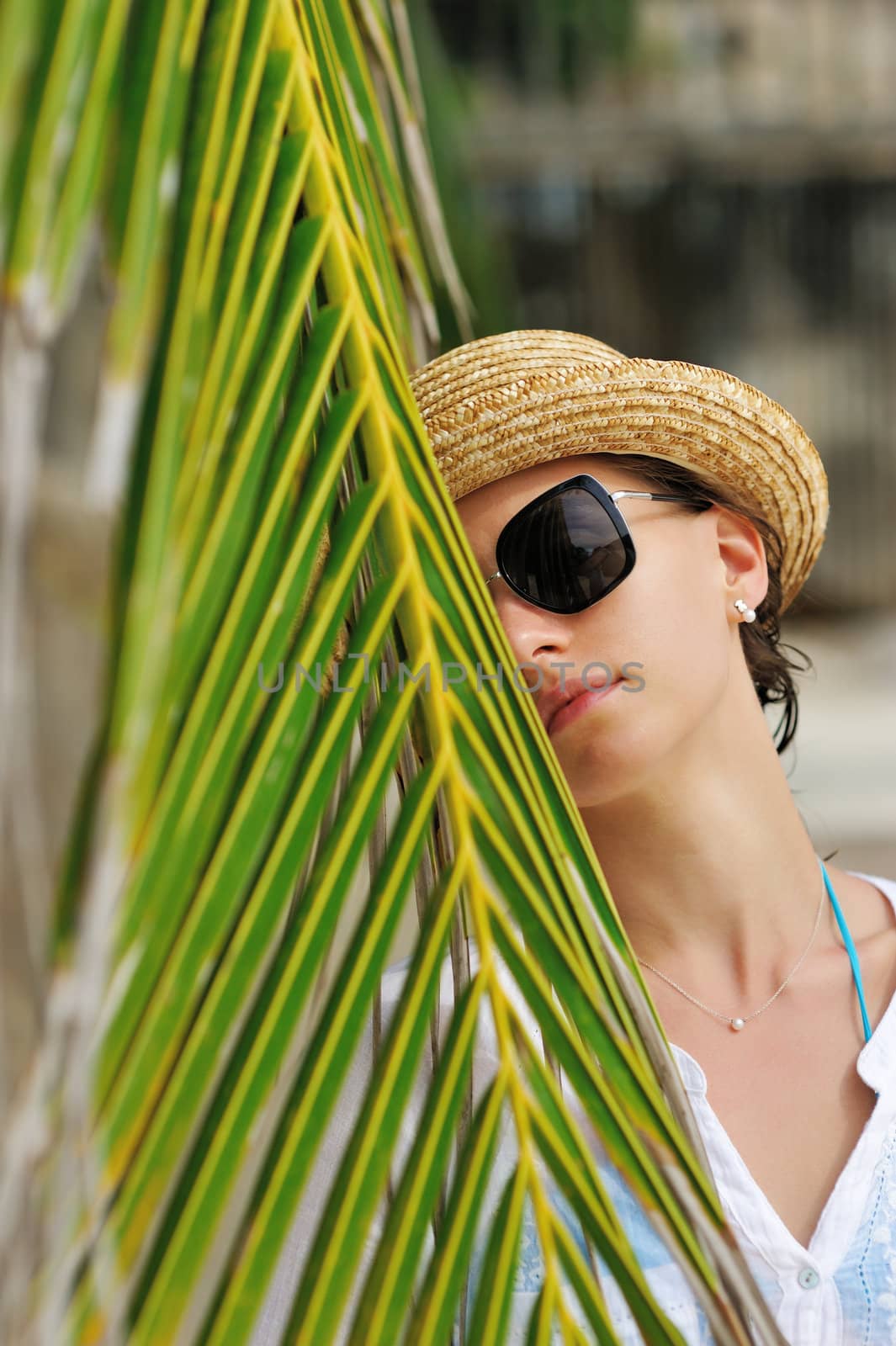 Woman in sunglasses near palm tree wearing hat