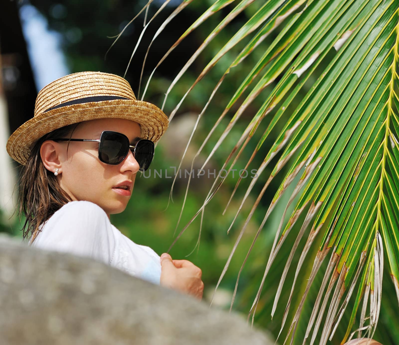 Woman in sunglasses near palm tree wearing hat