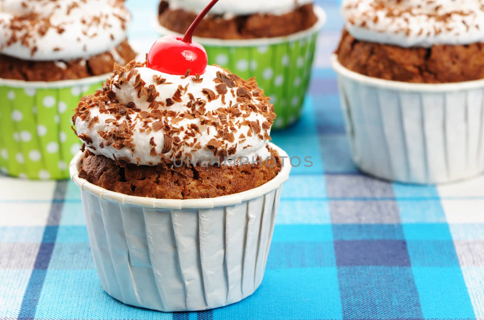 Cupcakes with whipped cream and cherry on a cloth
