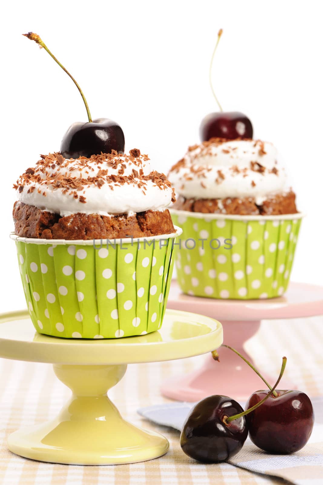 Cupcakes with whipped cream and cherry on a table