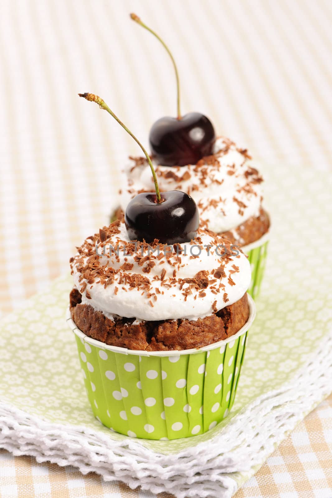 Cupcakes with whipped cream and cherry on a table