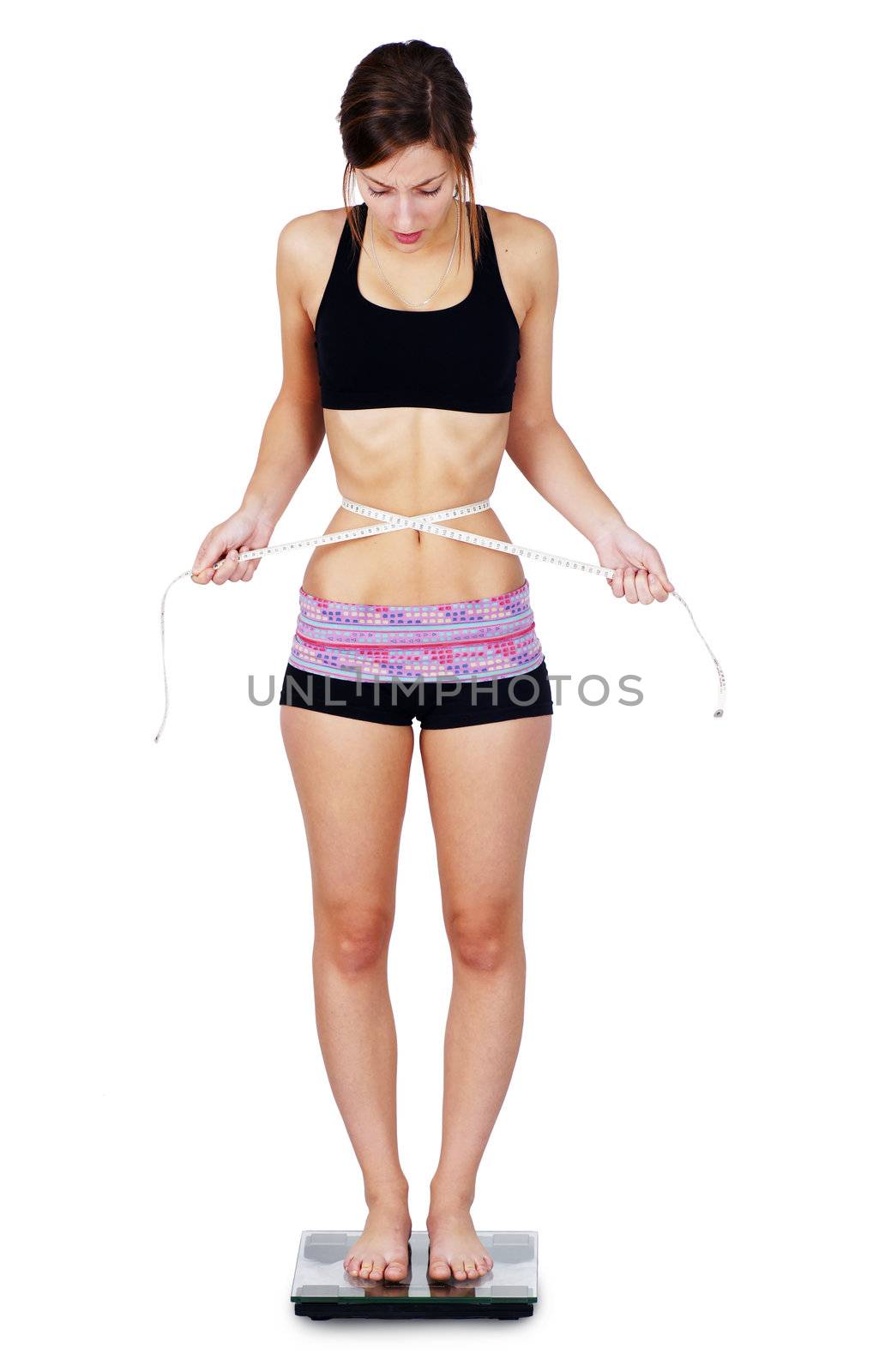 Very thin or anorexic young woman upset over her weight and waist measurements as she stands on scale.