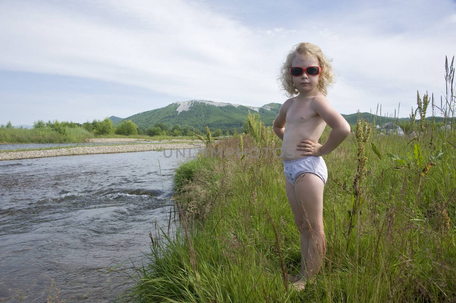 little girl playing on the river bank