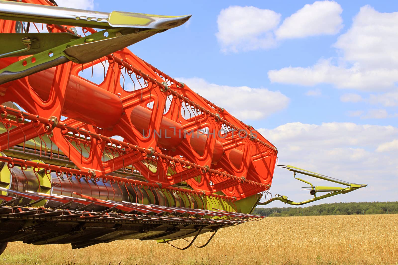 The front of a combine on a field of grain on a blue sky background