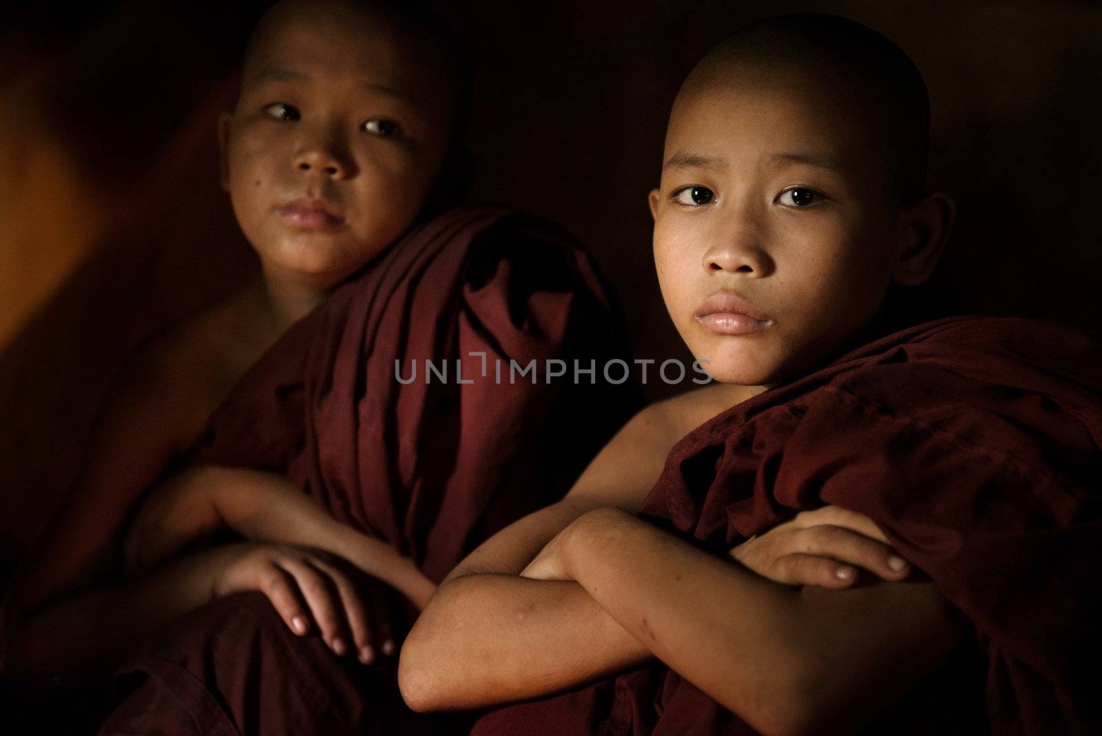 Young buddhist novice monk inside a temple background, low light setting