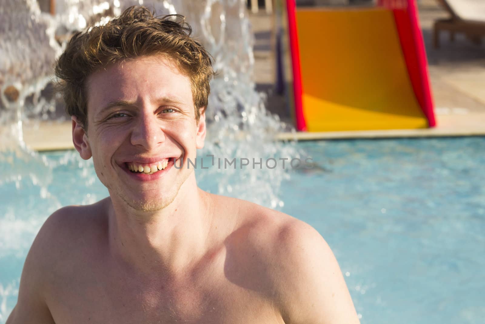 Happy man in the swimming pool with splashing water