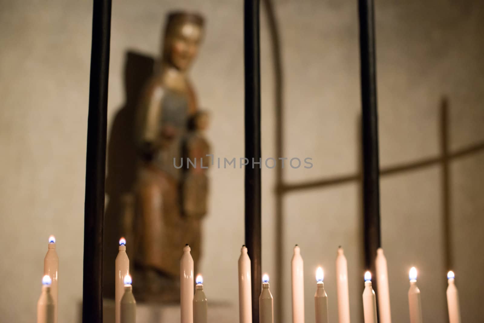 Lit candles in a church, with an an icon of Virgin Mary in the background
