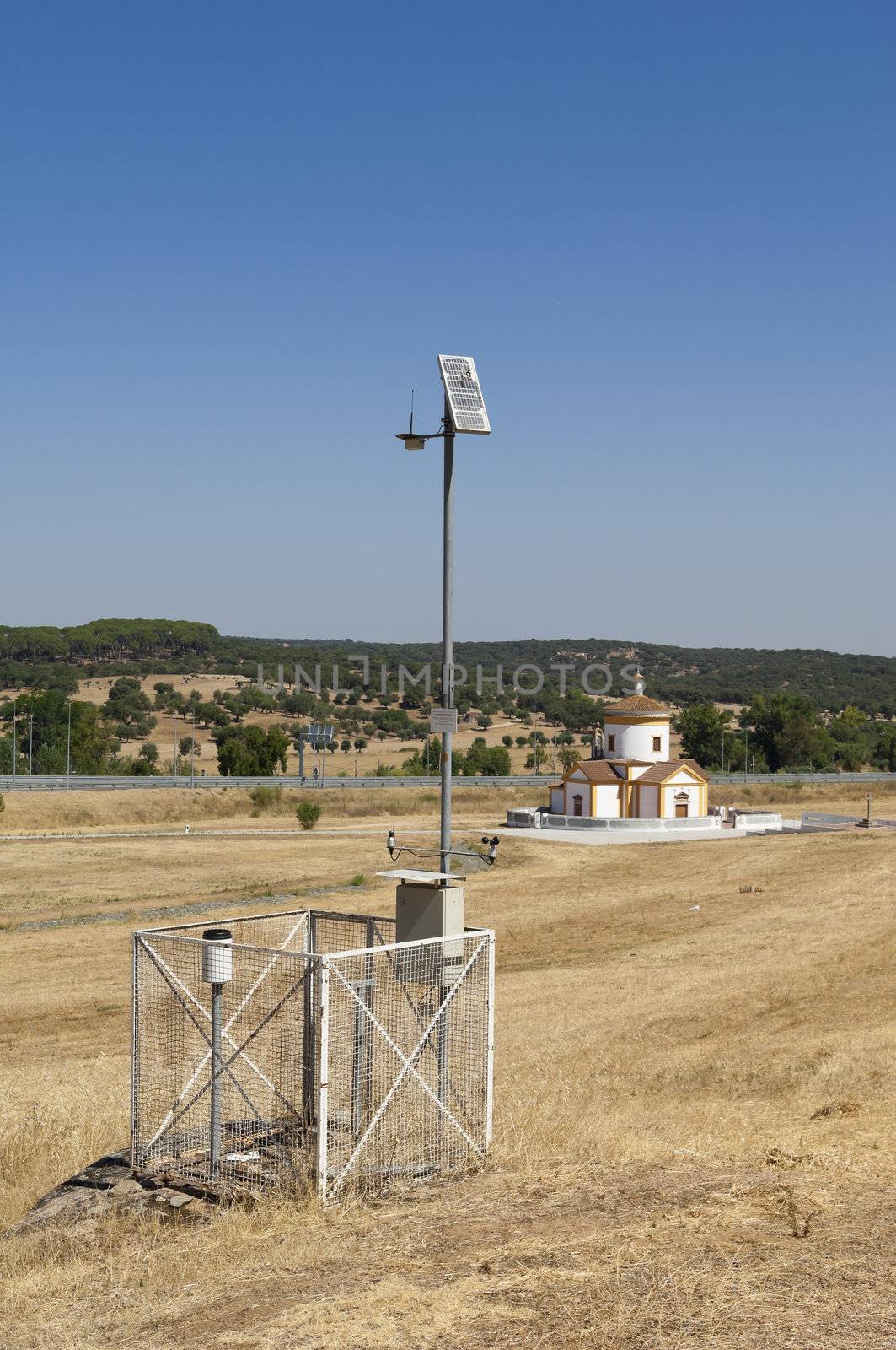 Automated weather station in a field with a church in the background, near Monforte, Portugal