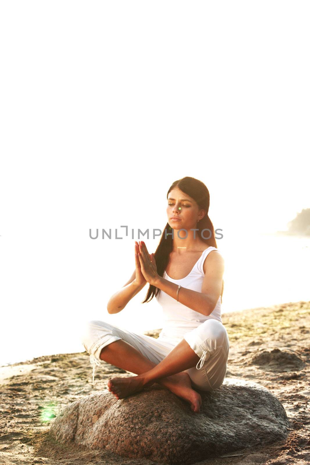 Young woman practicing yoga  near the ocean