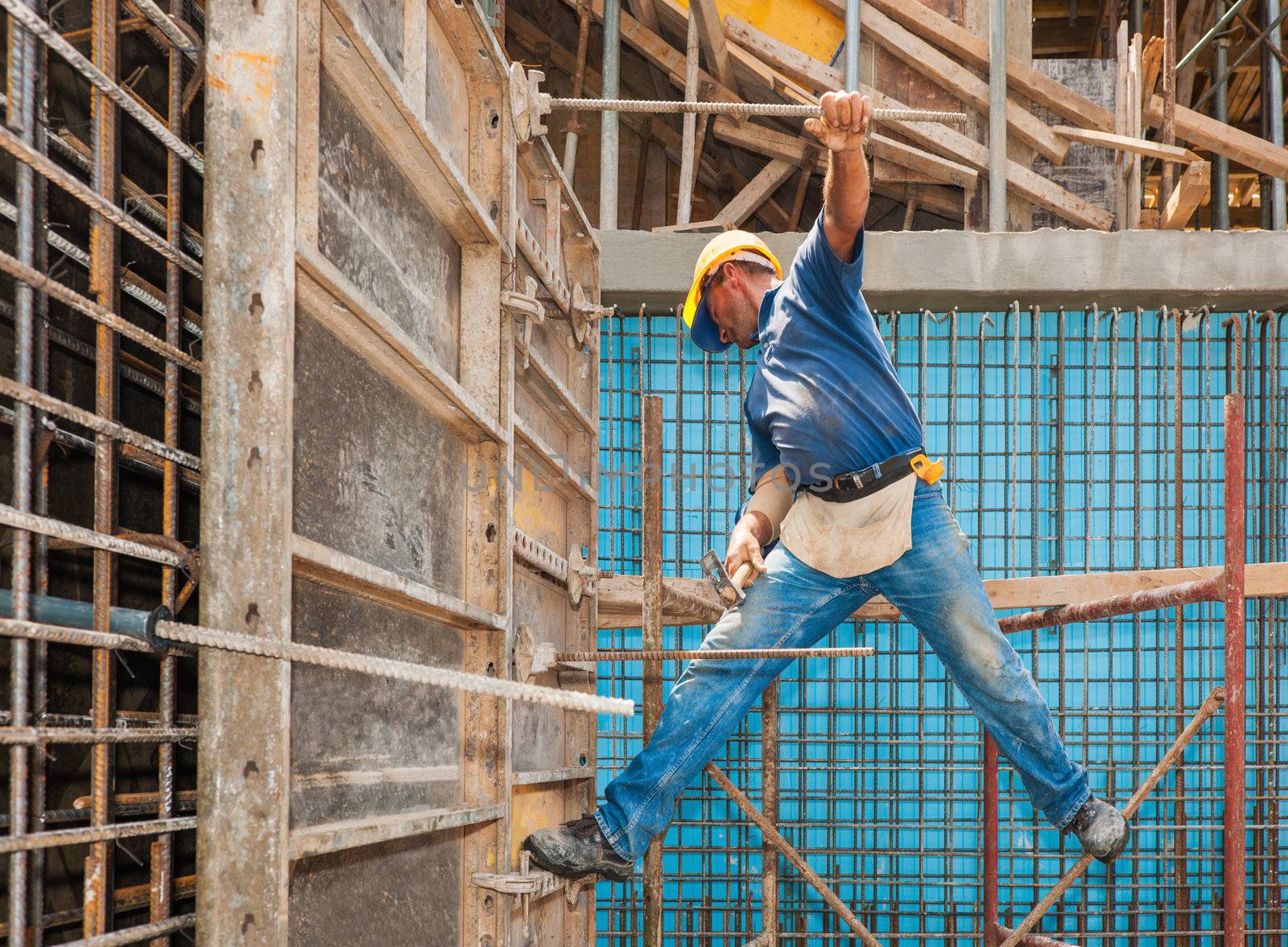 Construction worker balancing between scaffold and formwork fram by akarelias