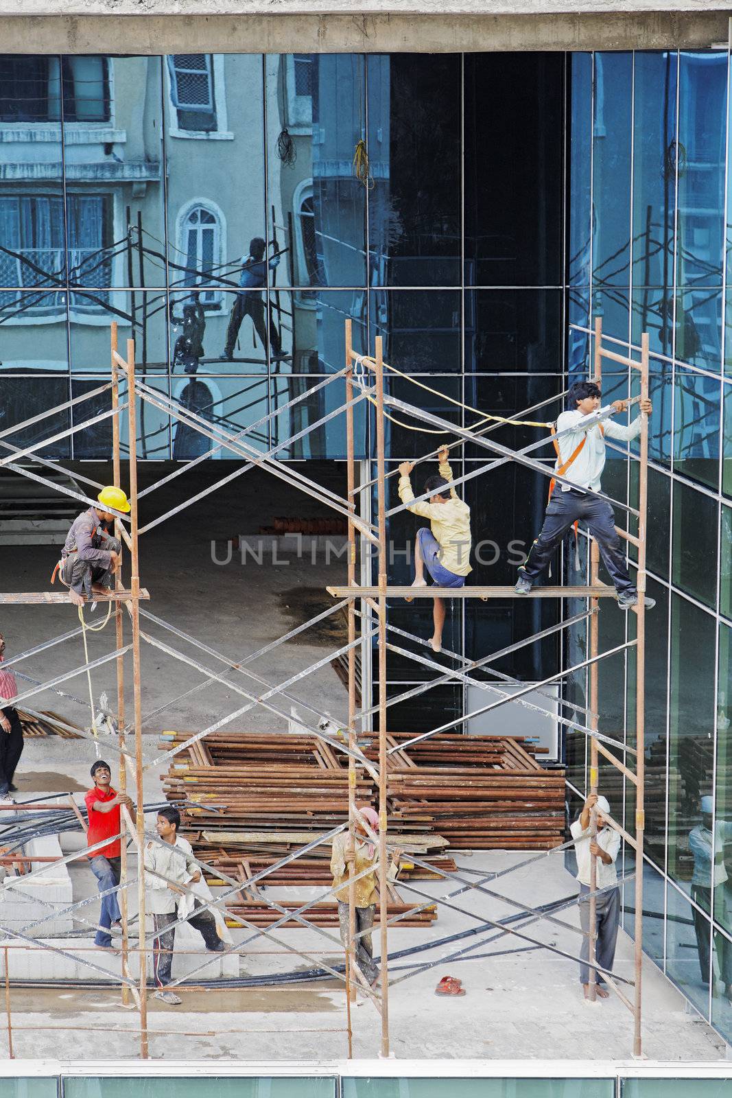 Scaffold workers erecting a scaffold on the upper floors of a high rise development on July 10, 2012 in Bombay, India. Local culture where workers operate in open toe slippers or bare feet.