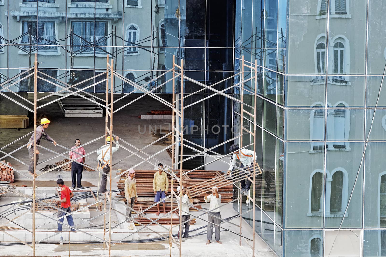 Scaffold workers erecting a scaffold on the upper floors of a high rise development on July 10, 2012 in Bombay, India. Local culture where workers operate in open toe slippers or bare feet.