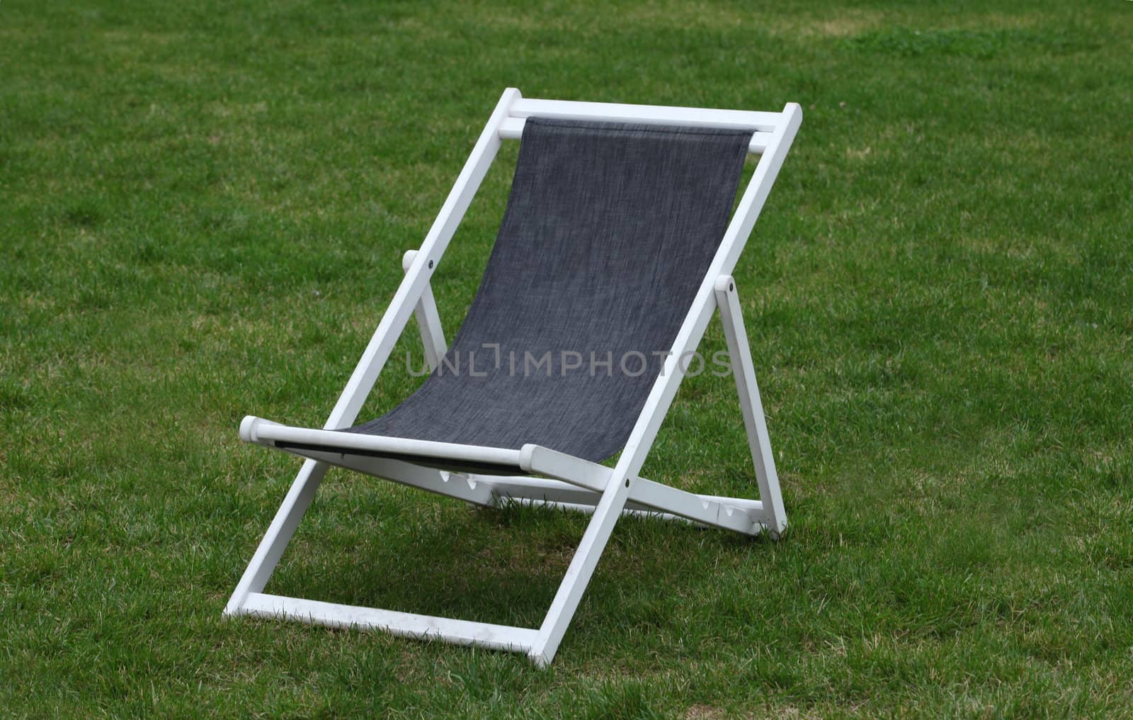 White wooden deck chair on green grass