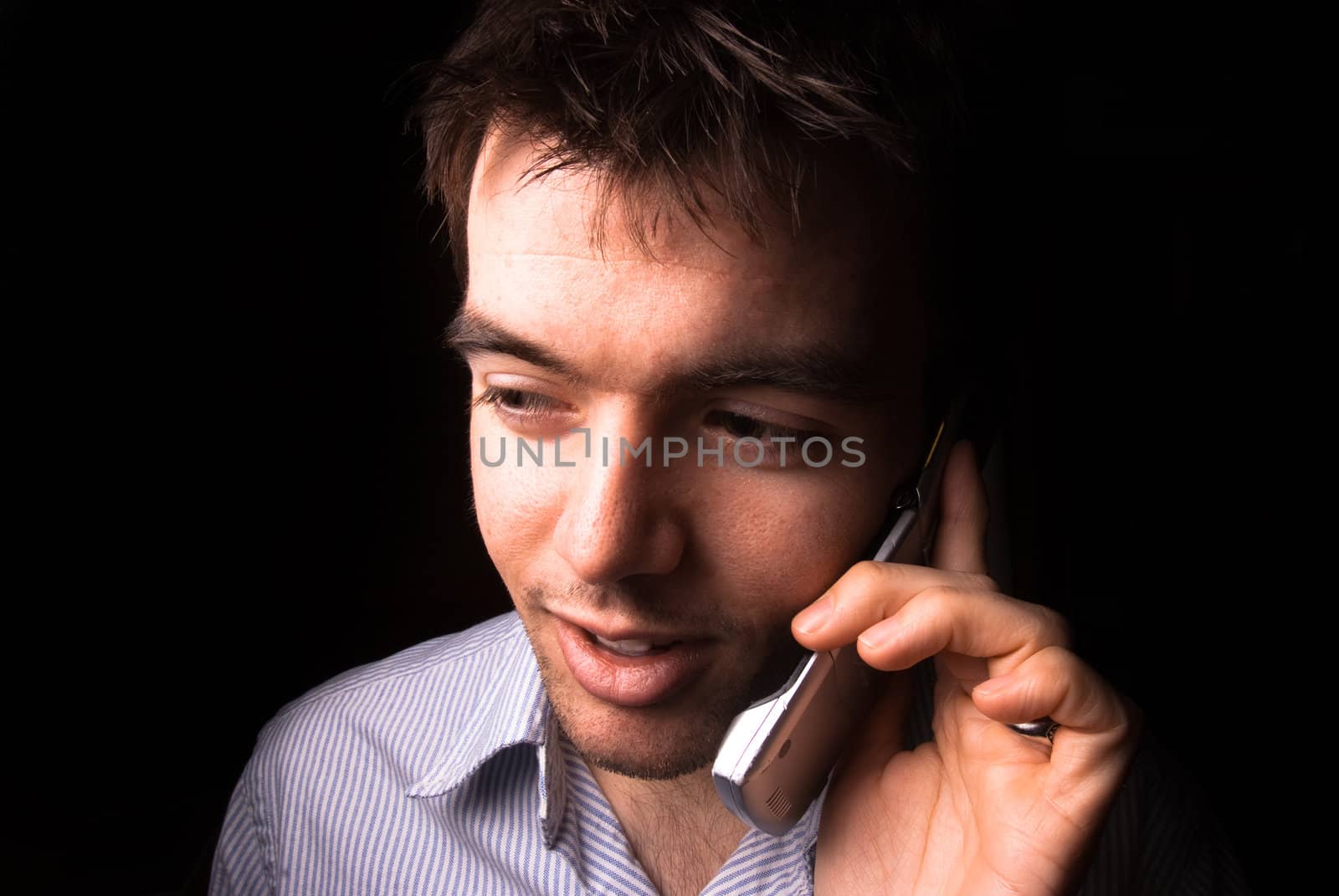Young man talking on a cell phone, black backgound
