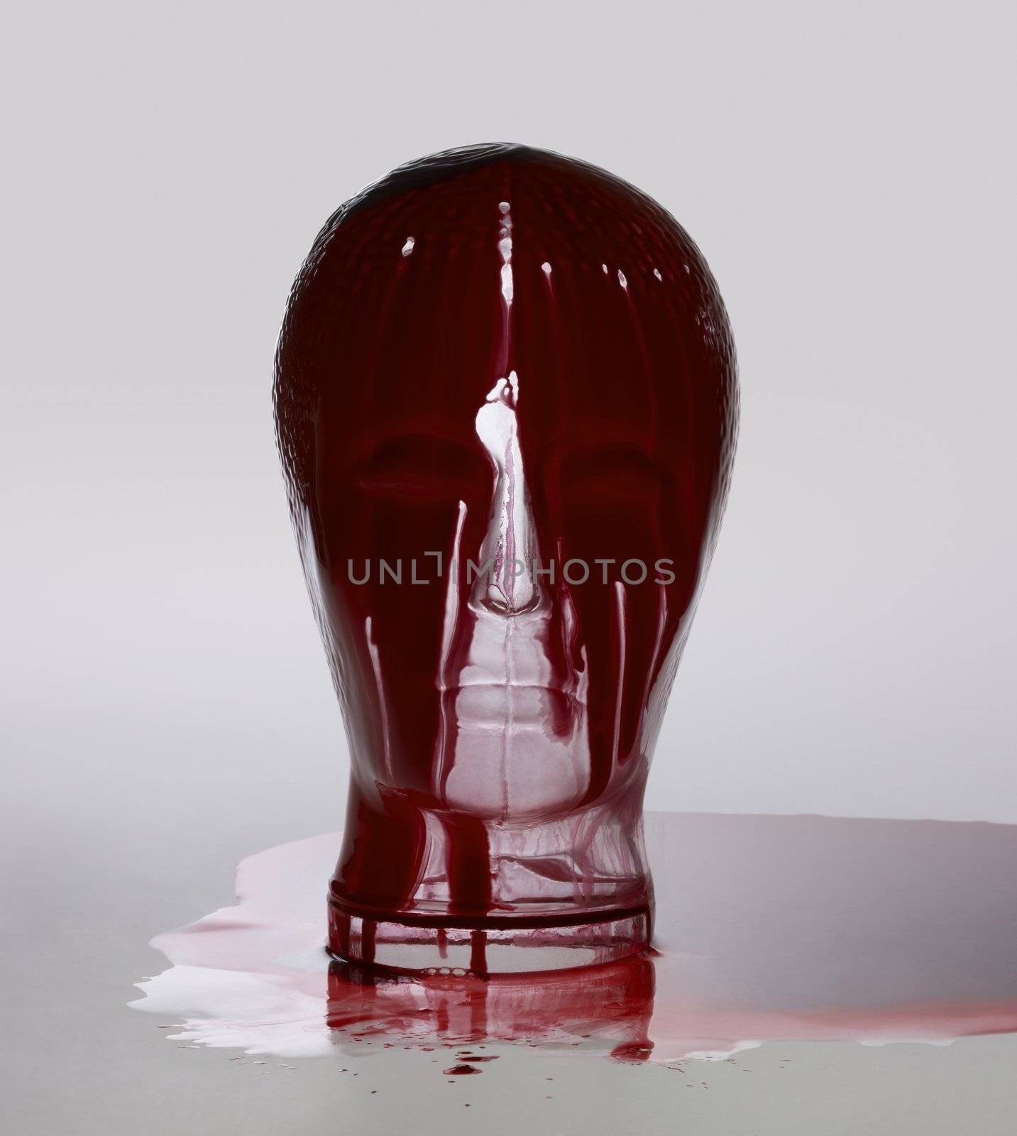 generic human "dummy" head made of glass, overwhelmed with red fluid in light grey back