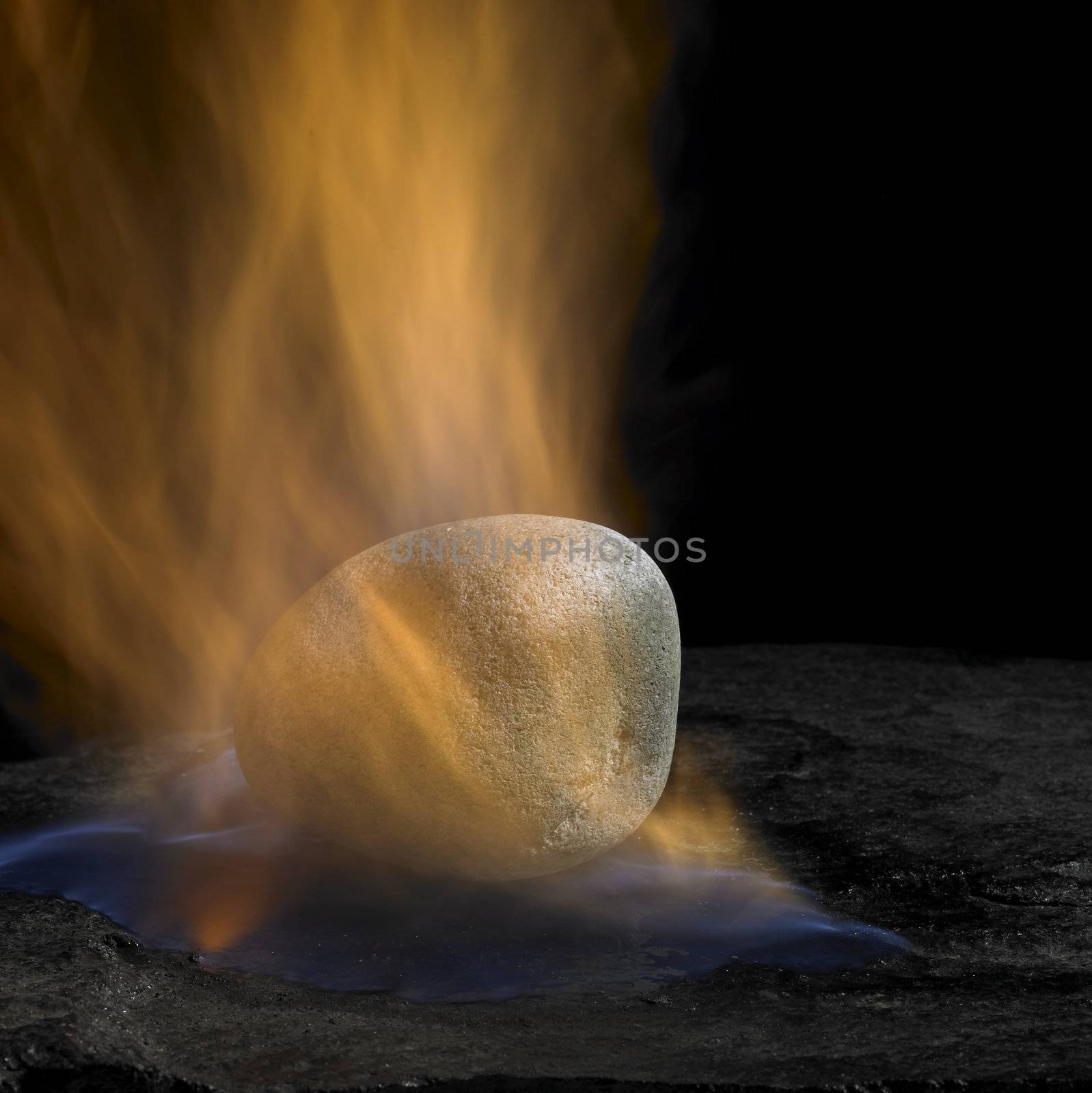 studio shot of a pebble and flames in dark back