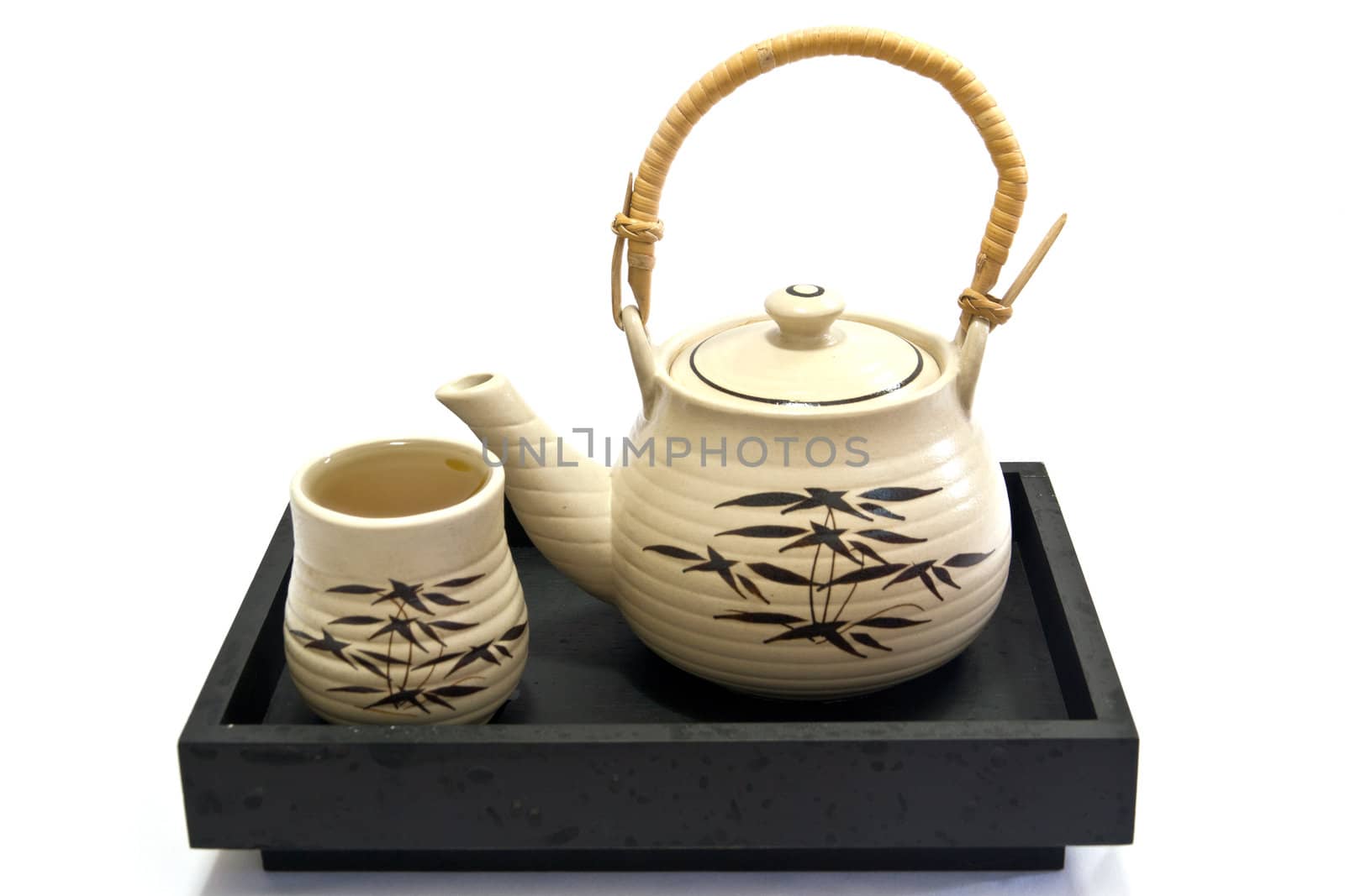 Teapot and teacup painting bamboo leaves on a black tray.