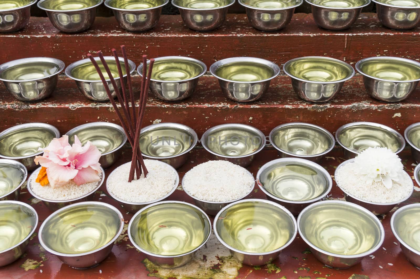many small bowls with water and rice around a temple in nepal