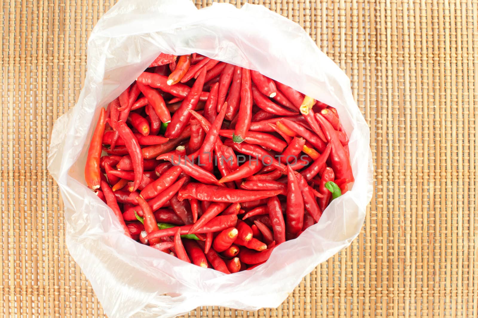 Red chilli in plastic bag on bamboo mat 