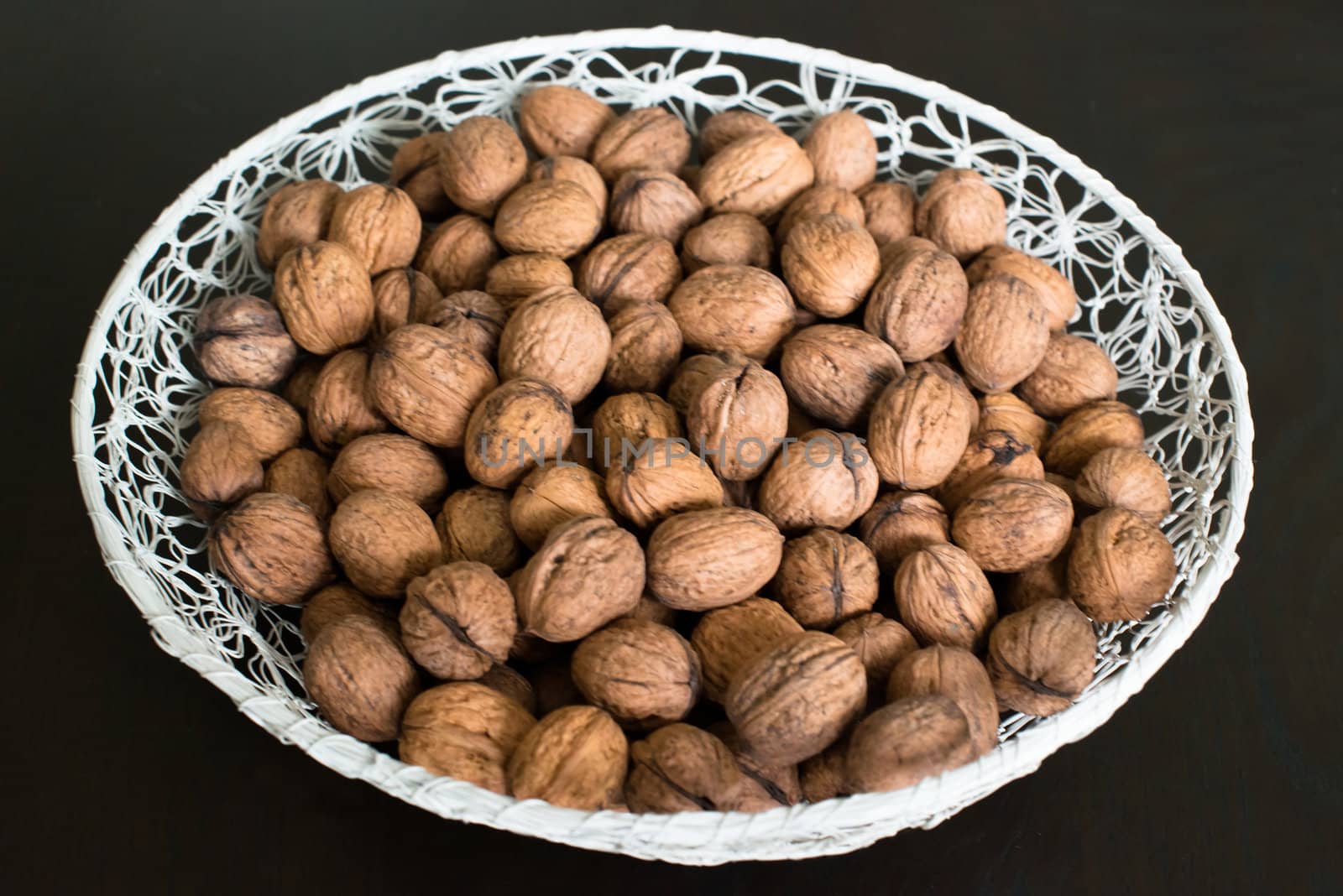 walnuts in a white basket on dark wooden table