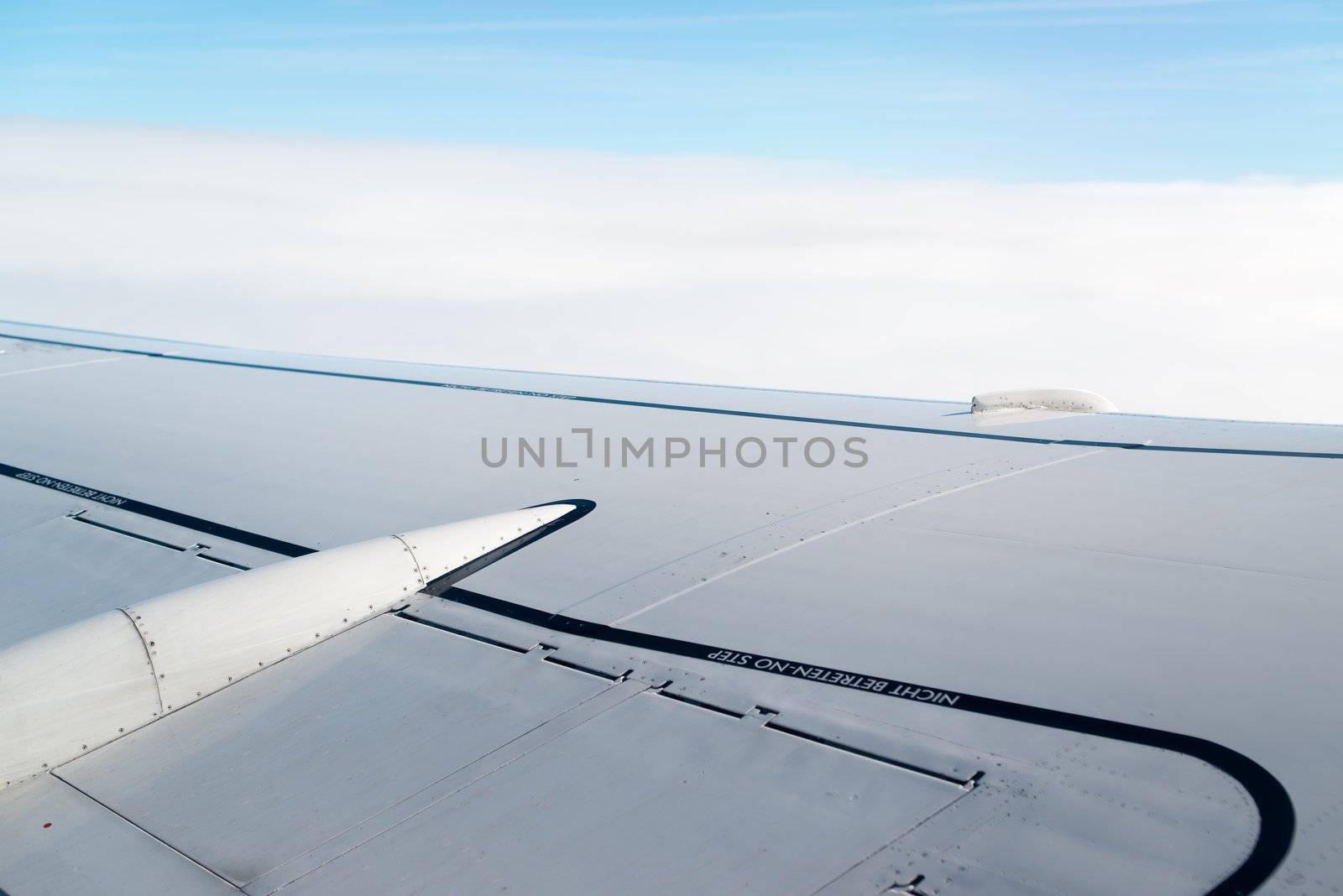 airplane wing, sky and clouds as seen through the cabin window
