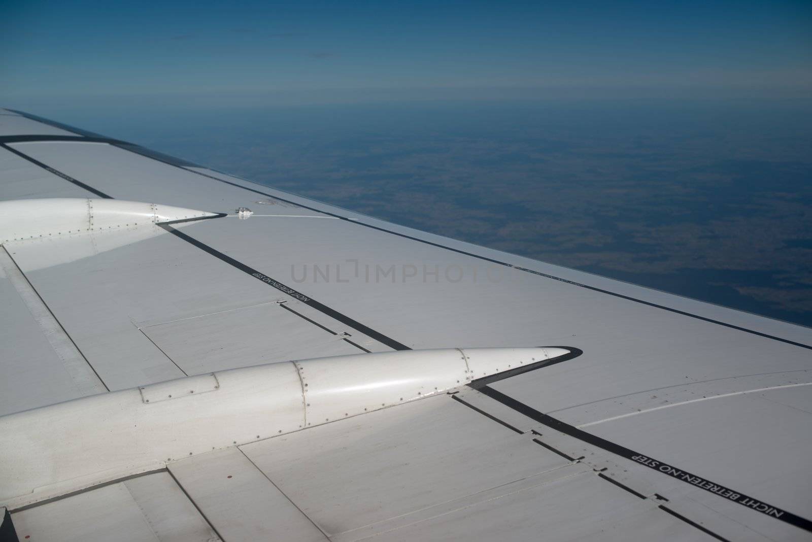 airplane wing, sky and clouds as seen through the cabin window