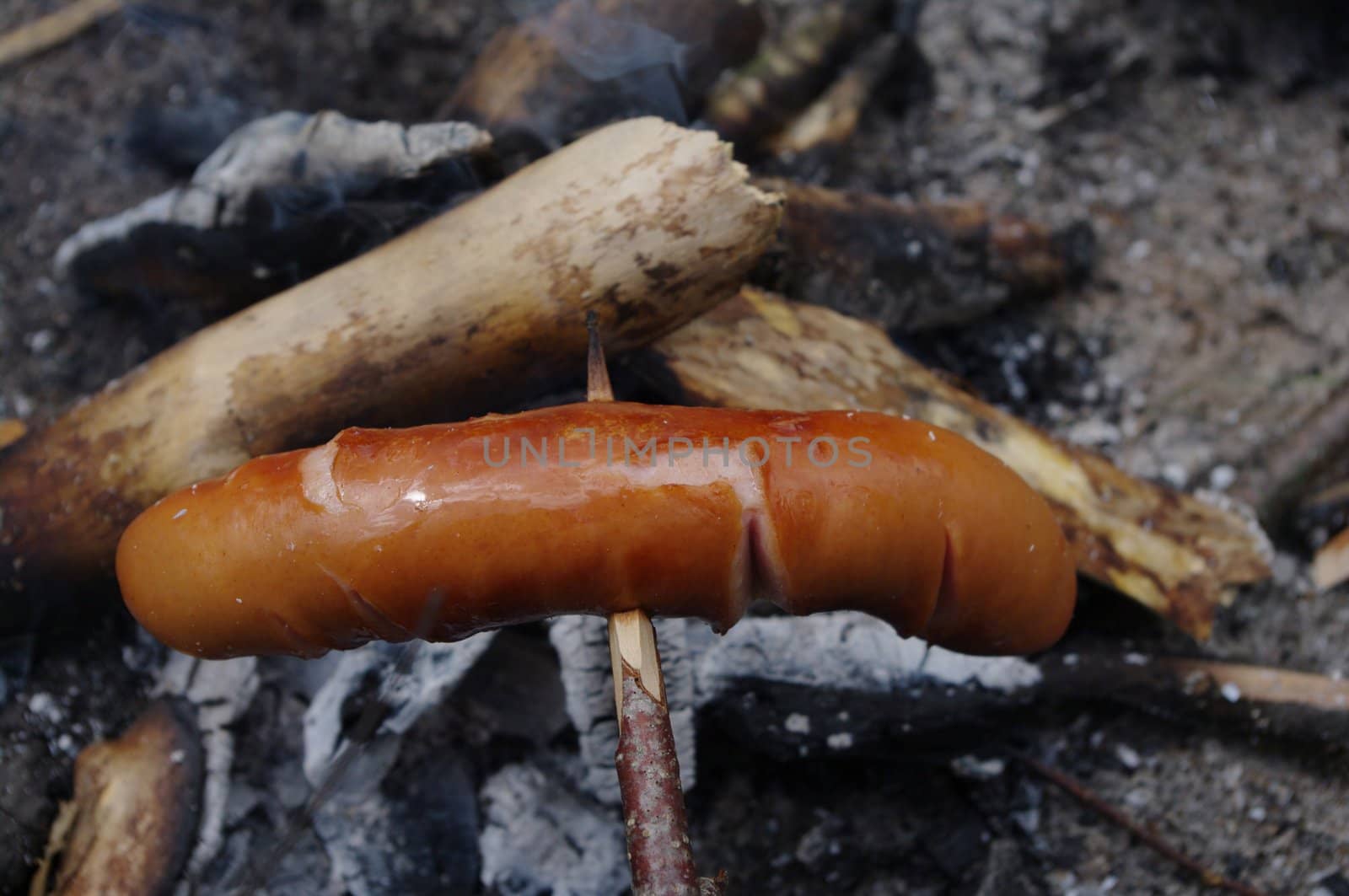 a sausage grilled on a camp fire