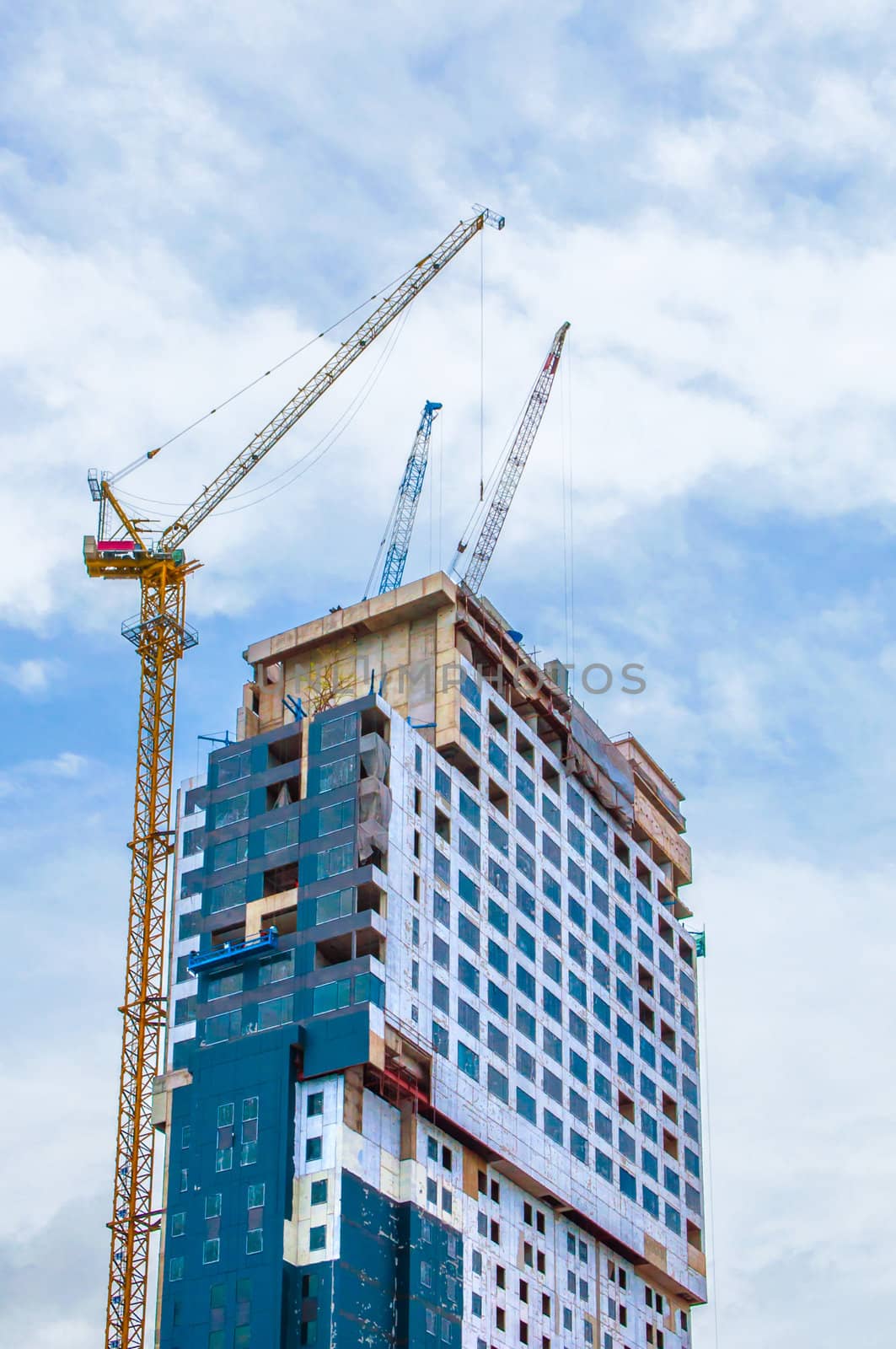 High-rise building construction site with cranes against cloudy sky