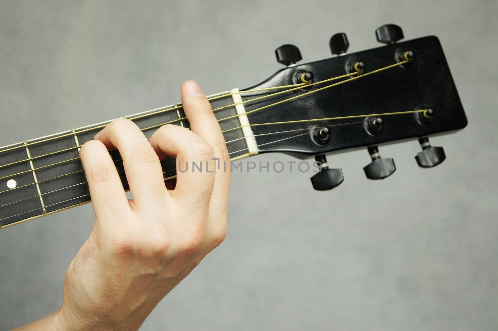 Hand holding F chord on guitar