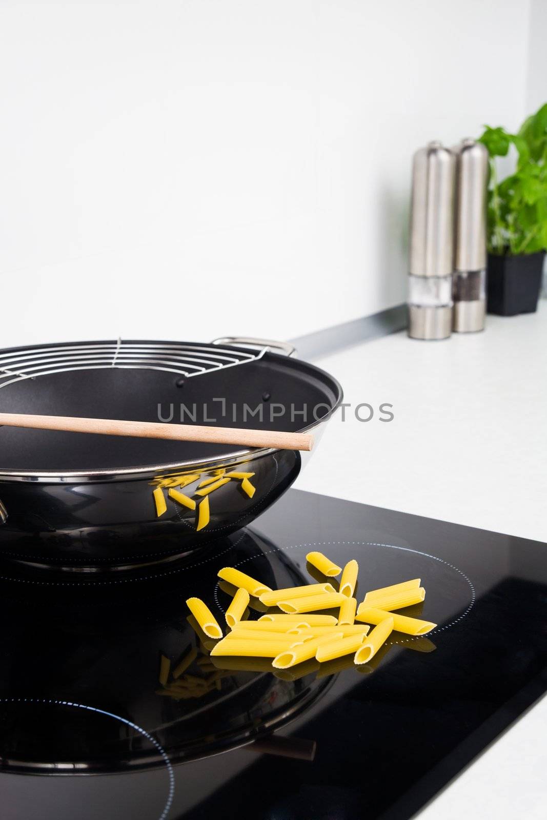 Frying pan, sticks and pasta in modern kitchen with induction stove