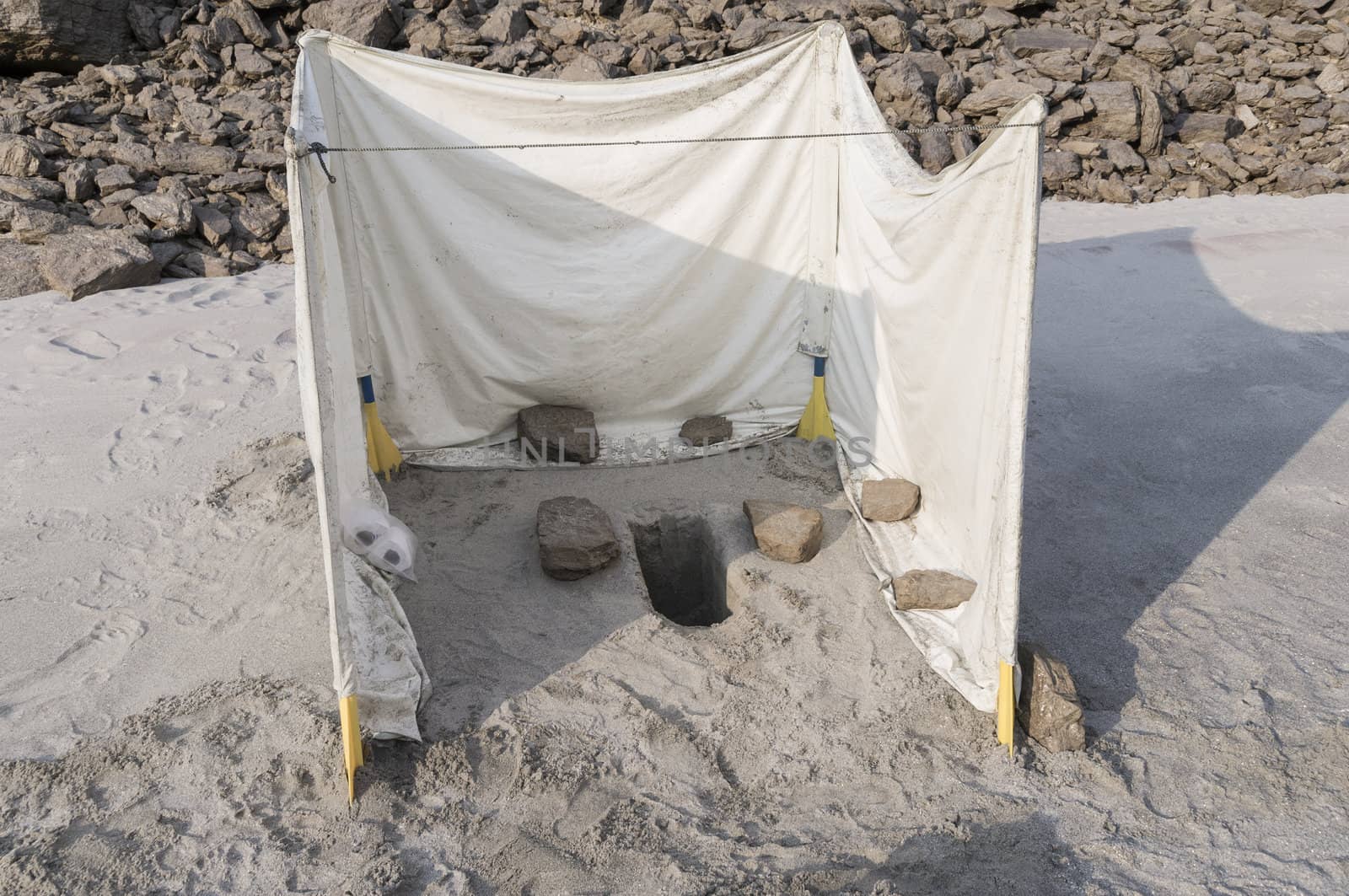 toilet used at an adventure trip. whole in the sand with a plastic foil around