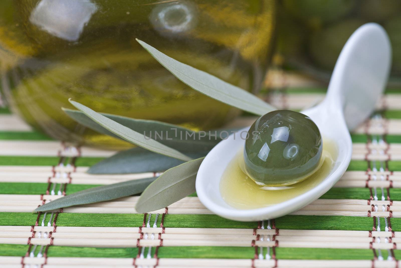 China spoon with olives a its leaves on a bamboo mat