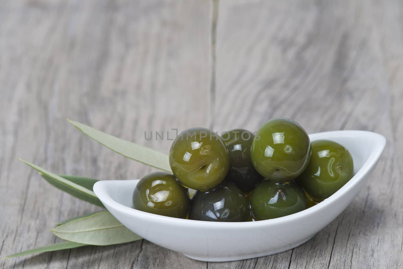 Saucer with olives on a wooden surface by angelsimon