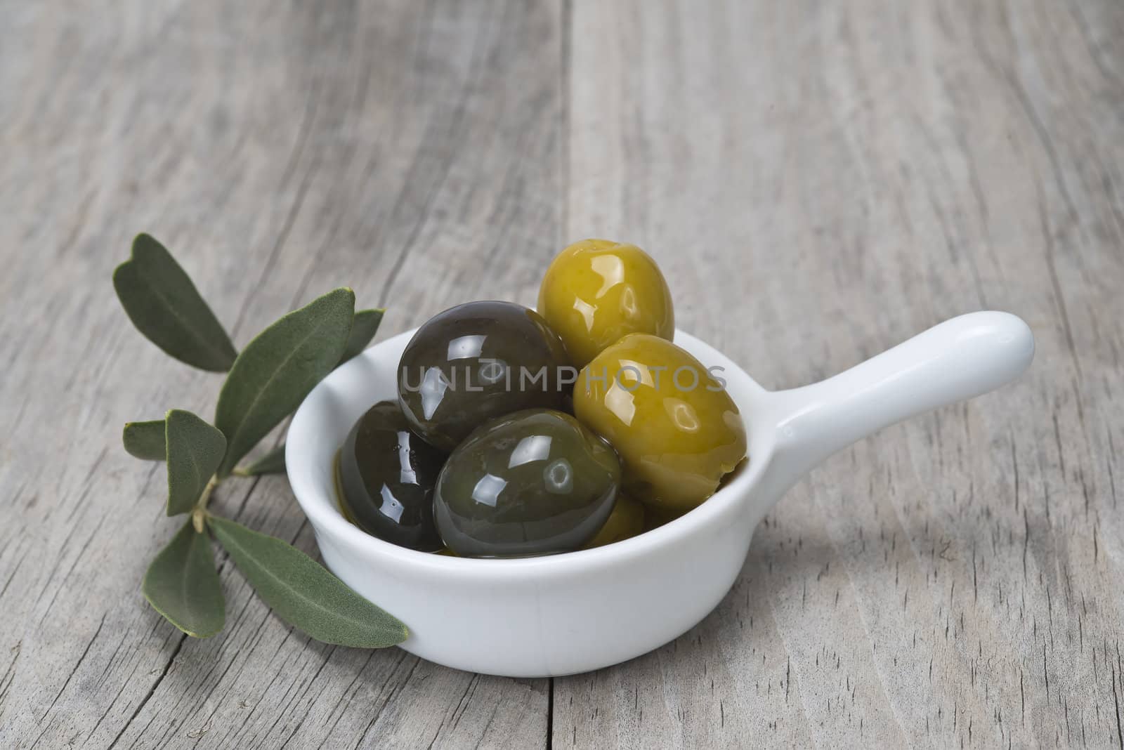 Saucer with olives on a wooden surface by angelsimon