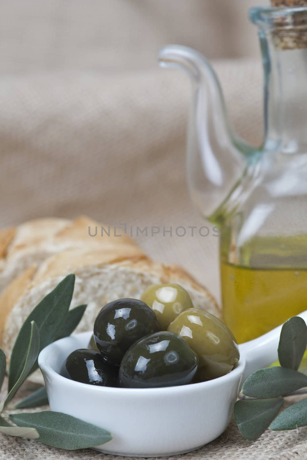 Olive oil with green olives and bread on a wooden surface