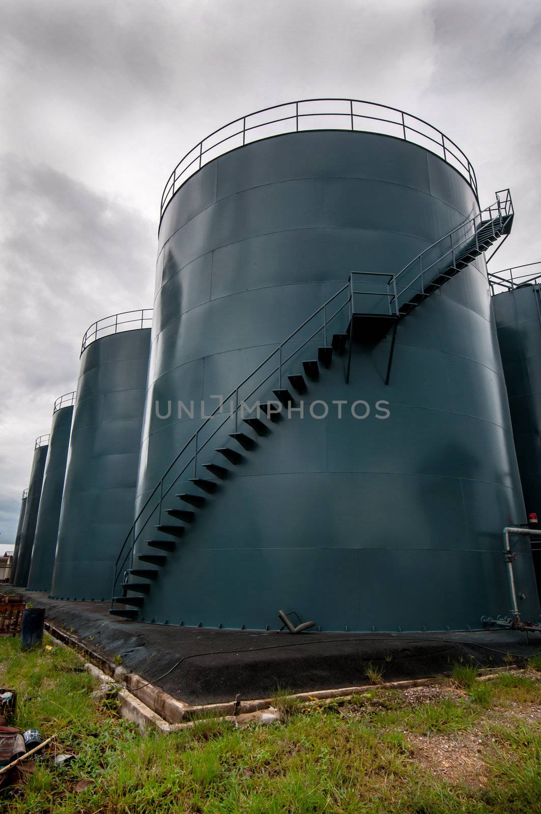  Vertical picture of  storage tanks and ladder on cloudy background