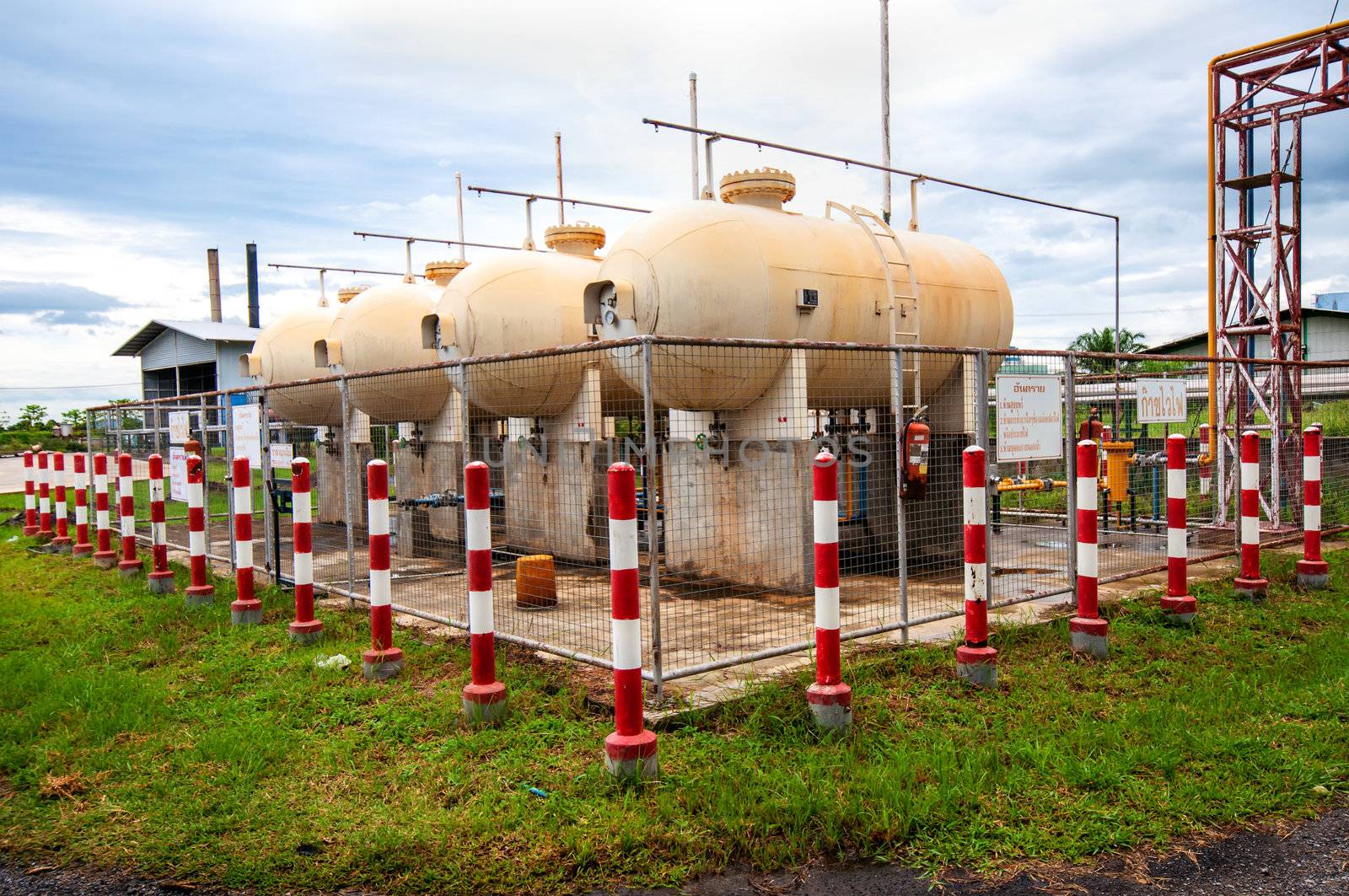 Liquid Petroleum Gas (LPG) storage unit inside a fence to prevent dangerous unauthorized intervention. Concept of Oil and Gas safety pre-caution measure.