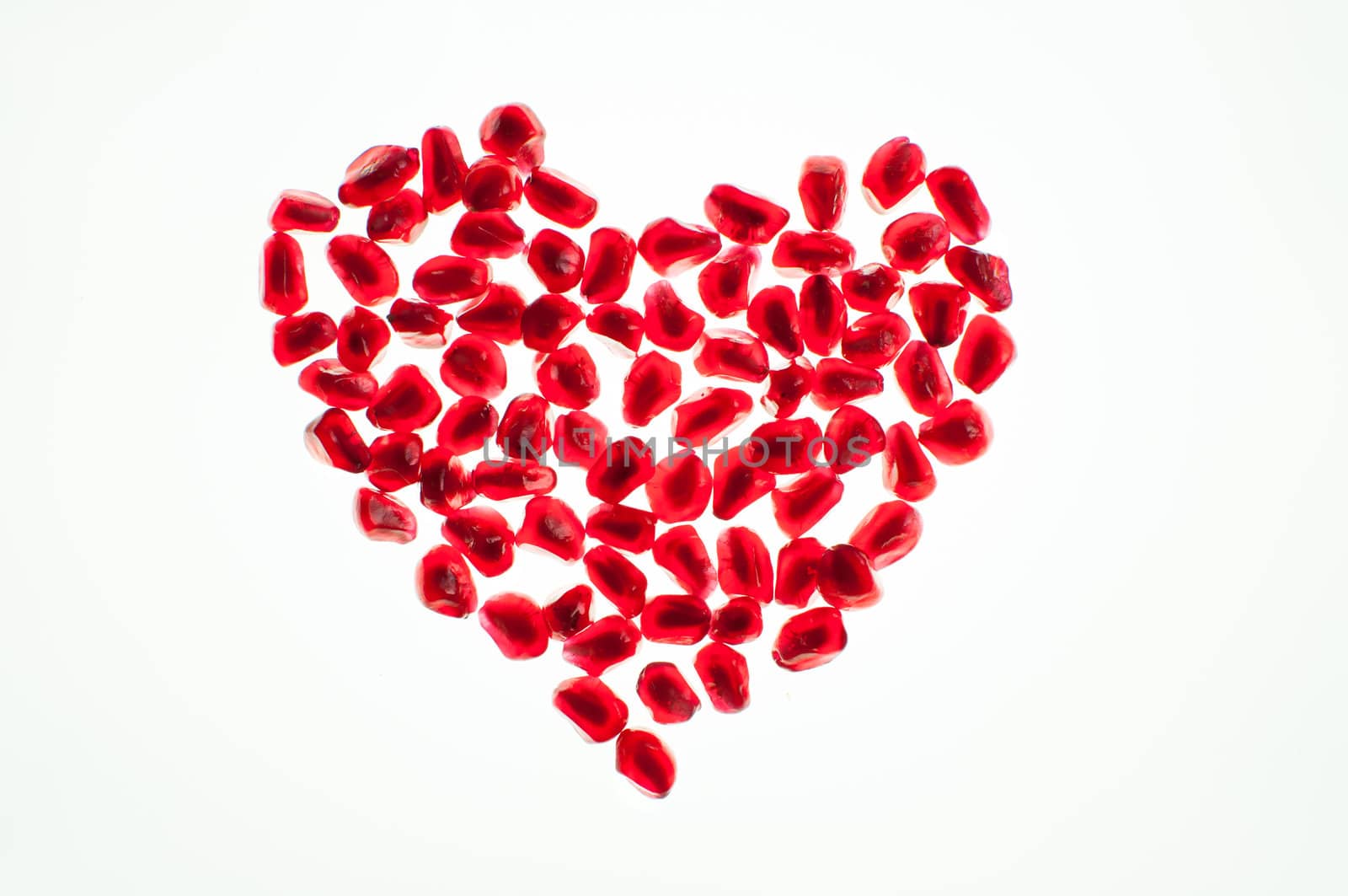 heart shape made by pomegranate seeds isolated on white