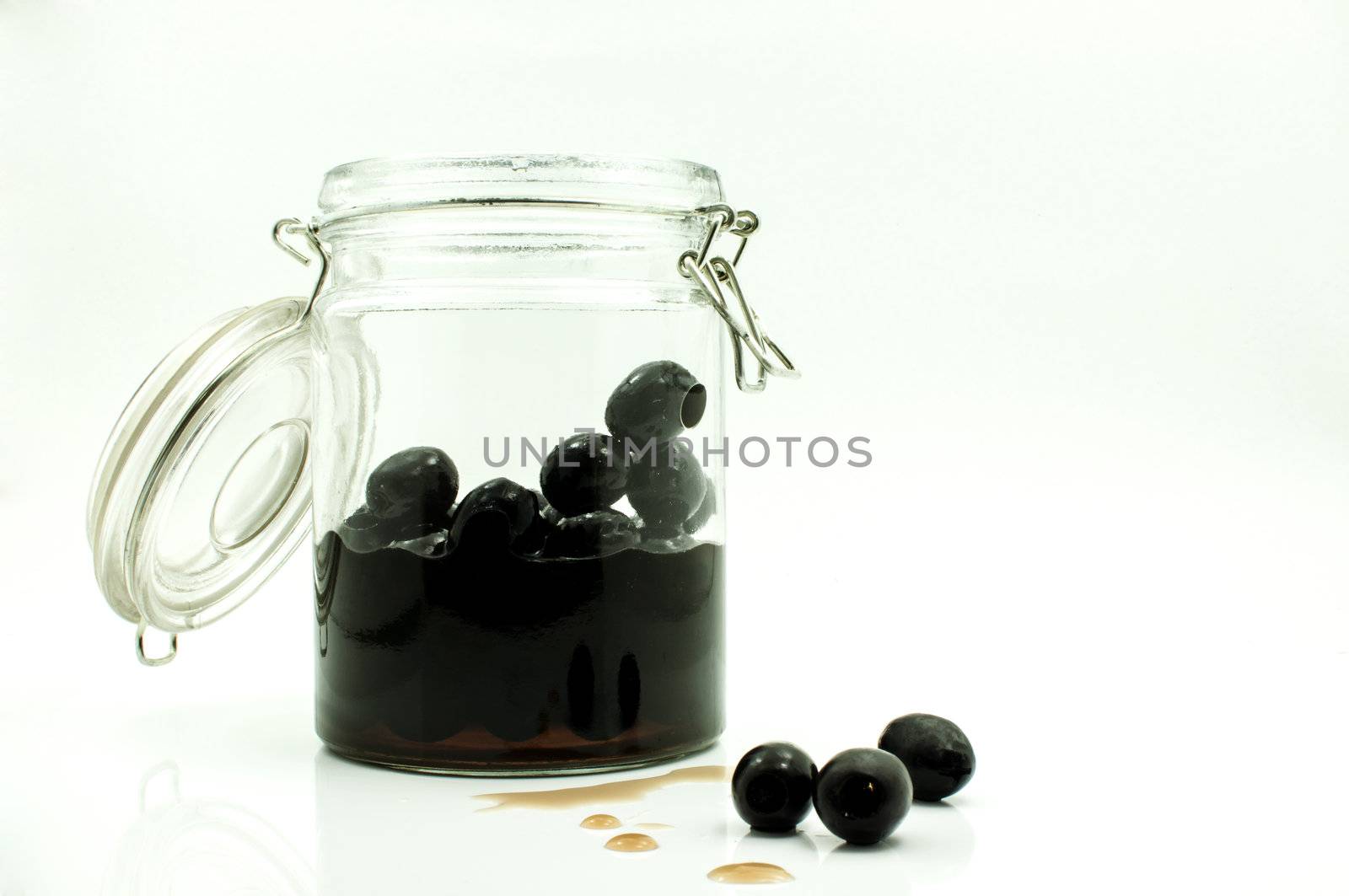 pickled black olives in glass bottle on a white background by TanawatPontchour