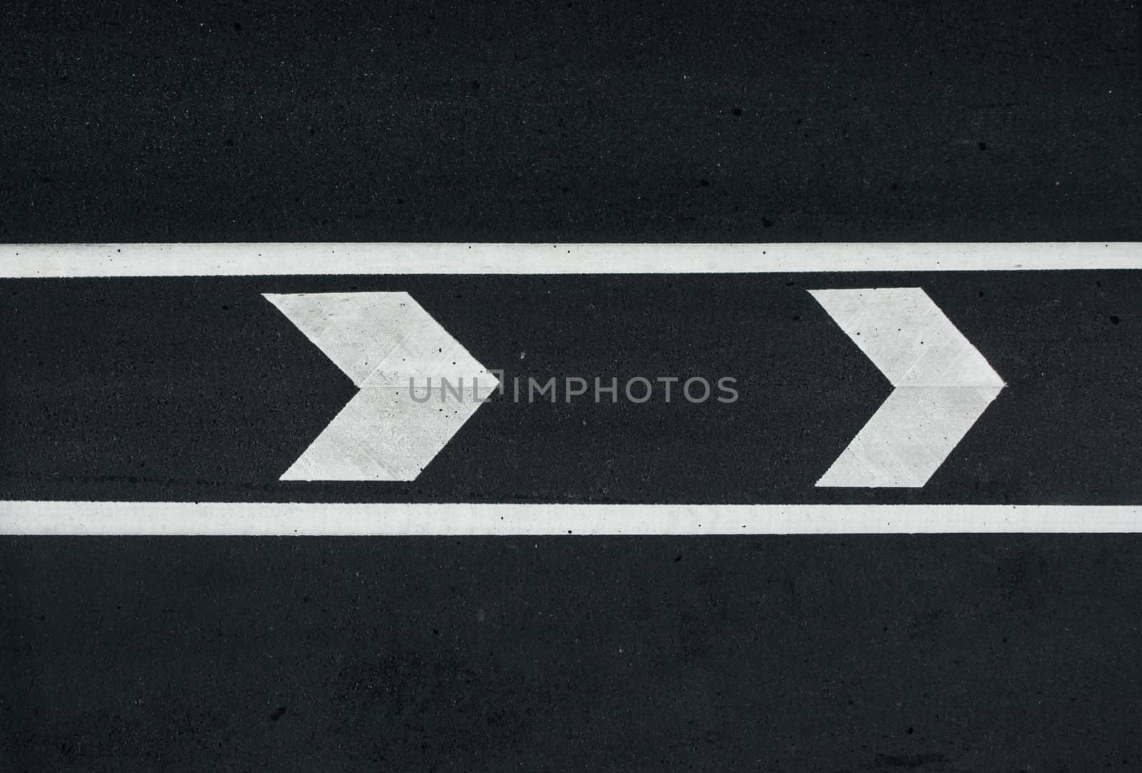 road marking: white arrows and line on the dark asphalt road.