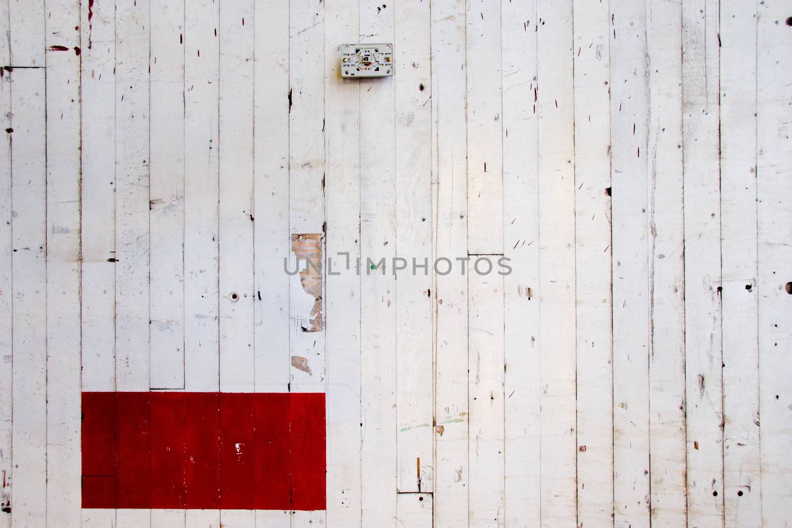 A very simple photo of a white wall with lines in the paint and a red rectangle of color.