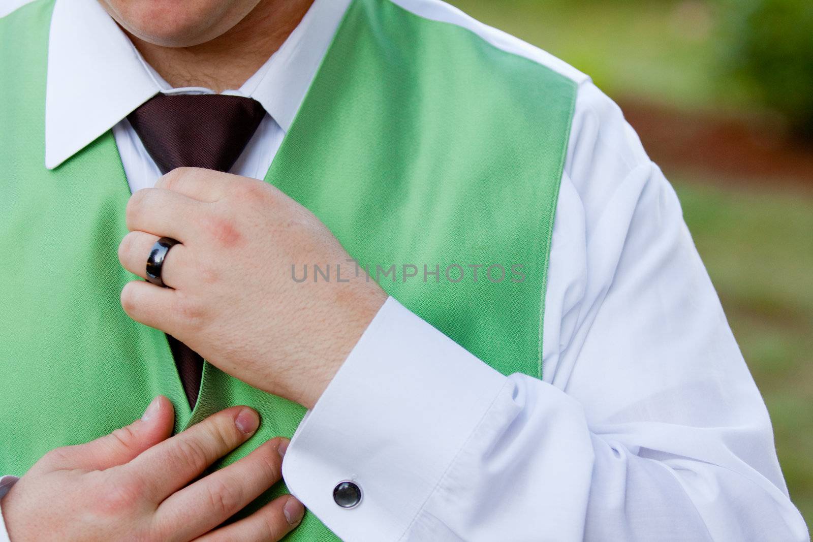 A groom is messing with his tie and vest at a wedding reception.